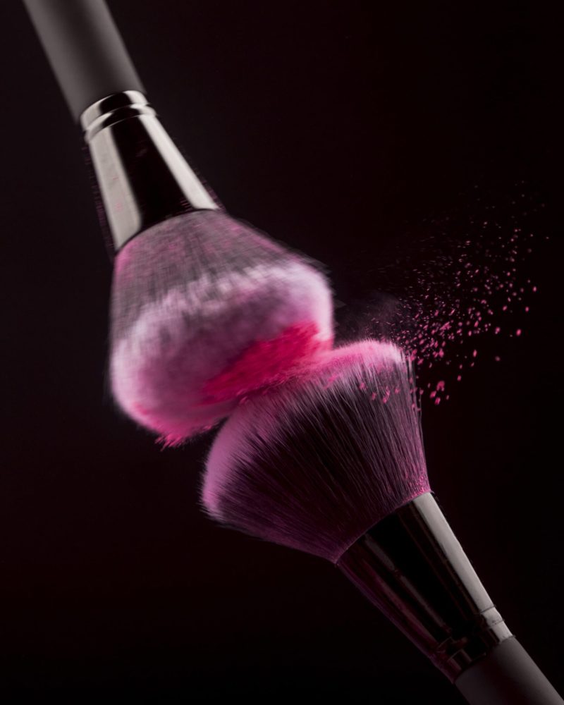 rubbing-professional-makeup-brushes-with-pink-powder-min